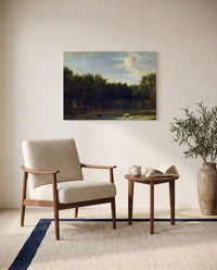 The Edge of a Wood by Adriaen van de Velde as a stretched canvas above a linen lounge chair in a reading corner