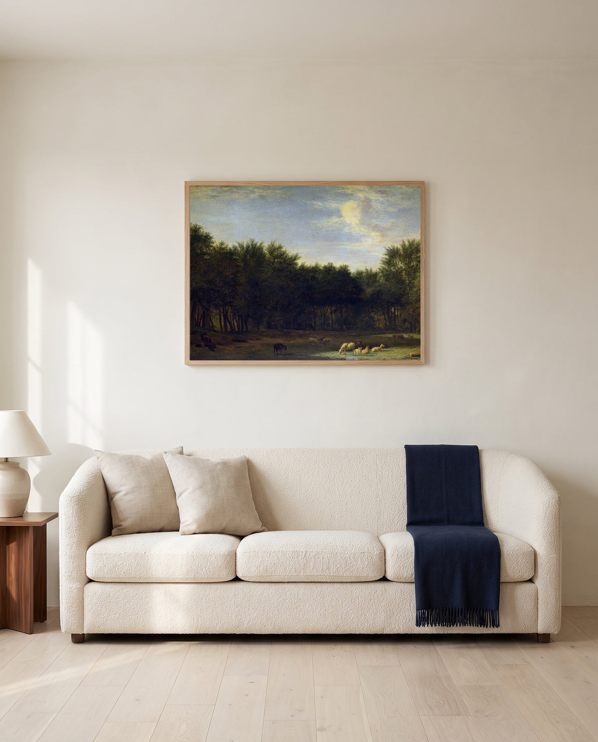 The Edge of a Wood by Adriaen van de Velde framed in natural oak above a cream sofa in a warm living room