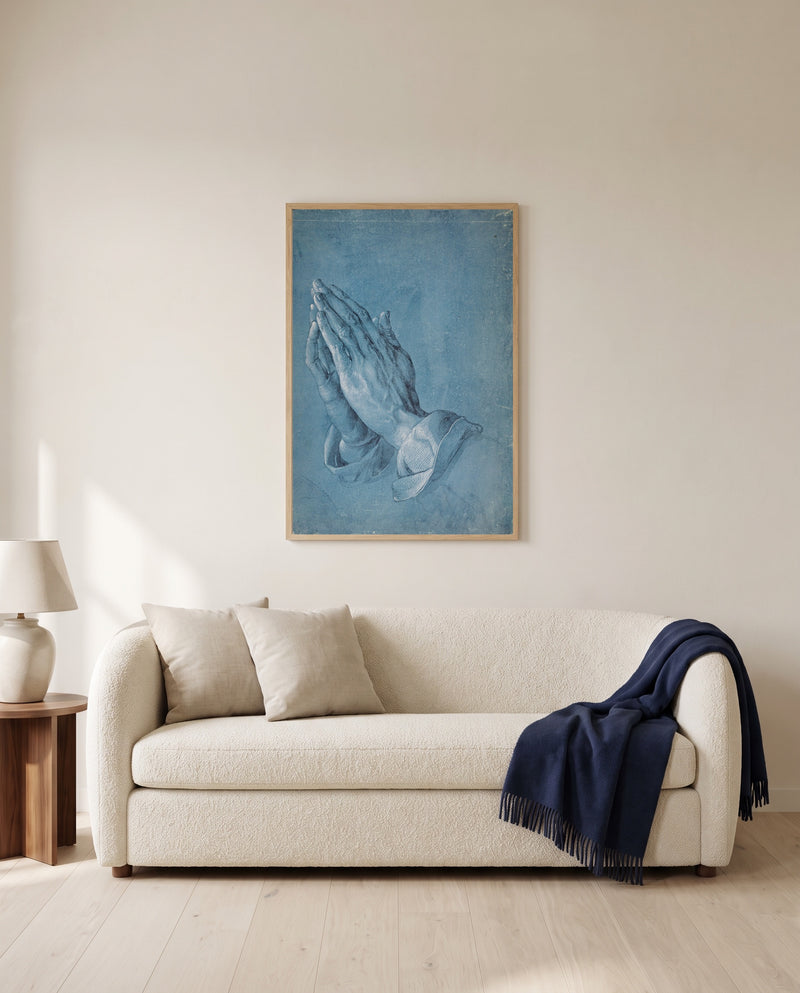 Praying Hands by Albrecht Dürer framed in natural oak above a cream sofa in a warm living room