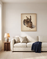 Young Hare by Albrecht Dürer framed in natural oak above a cream sofa in a warm living room