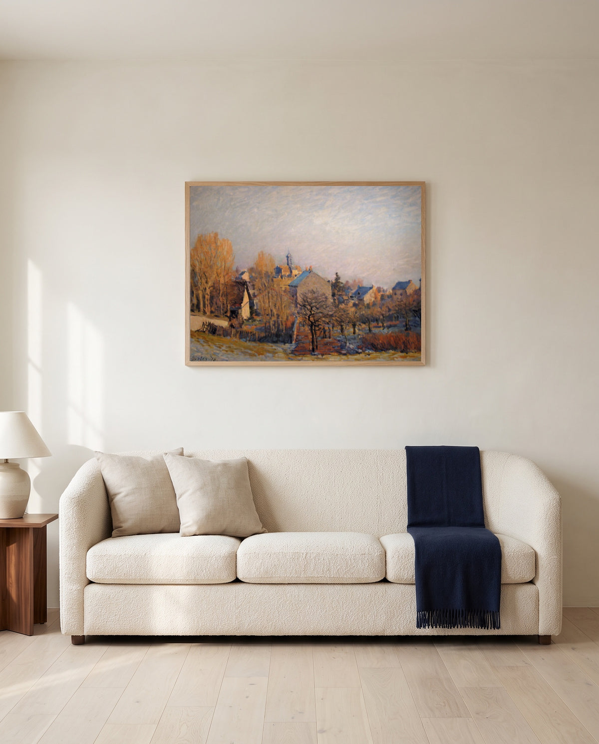 Frost in Louveciennes by Alfred Sisley framed in natural oak above a cream sofa in a warm living room
