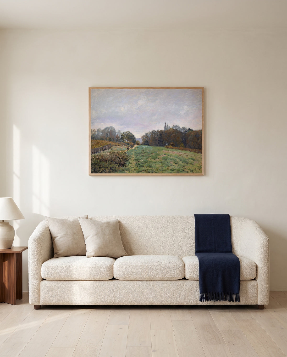 Landscape at Louveciennes by Alfred Sisley framed in natural oak above a cream sofa in a warm living room
