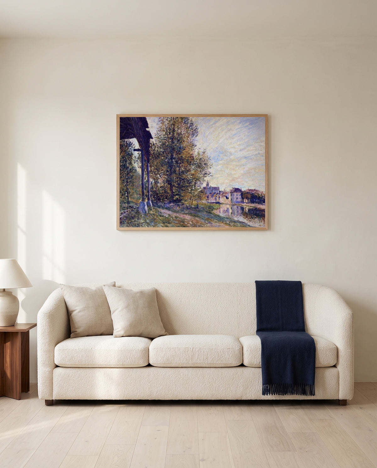 Near Moret-sur-Loing by Alfred Sisley framed in natural oak above a cream sofa in a warm living room