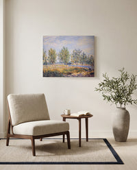 Poplars on a River Bank by Alfred Sisley as a stretched canvas above a linen lounge chair in a reading corner