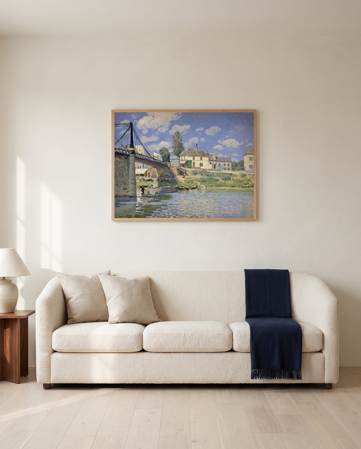 Bridge at Villeneuve by Alfred Sisley framed in natural oak above a cream sofa in a warm living room