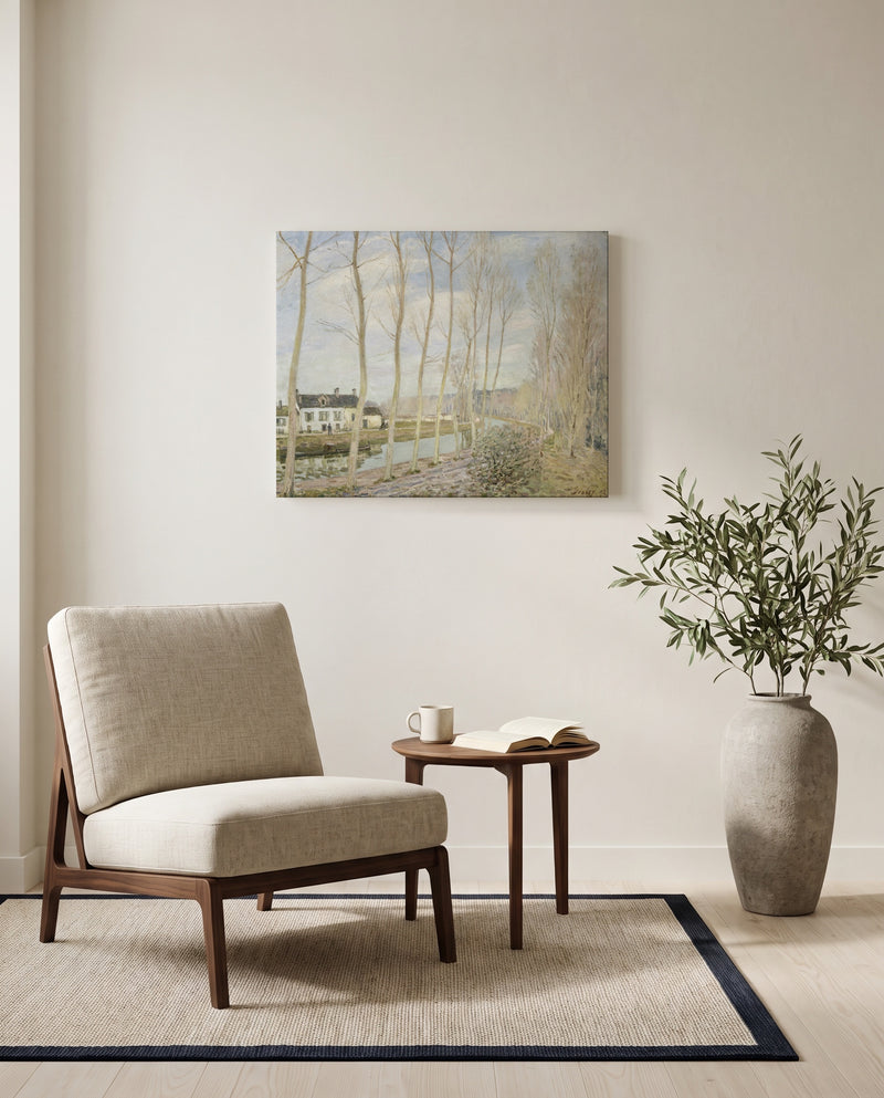 The Canal du Loing by Alfred Sisley as a stretched canvas above a linen lounge chair in a reading corner