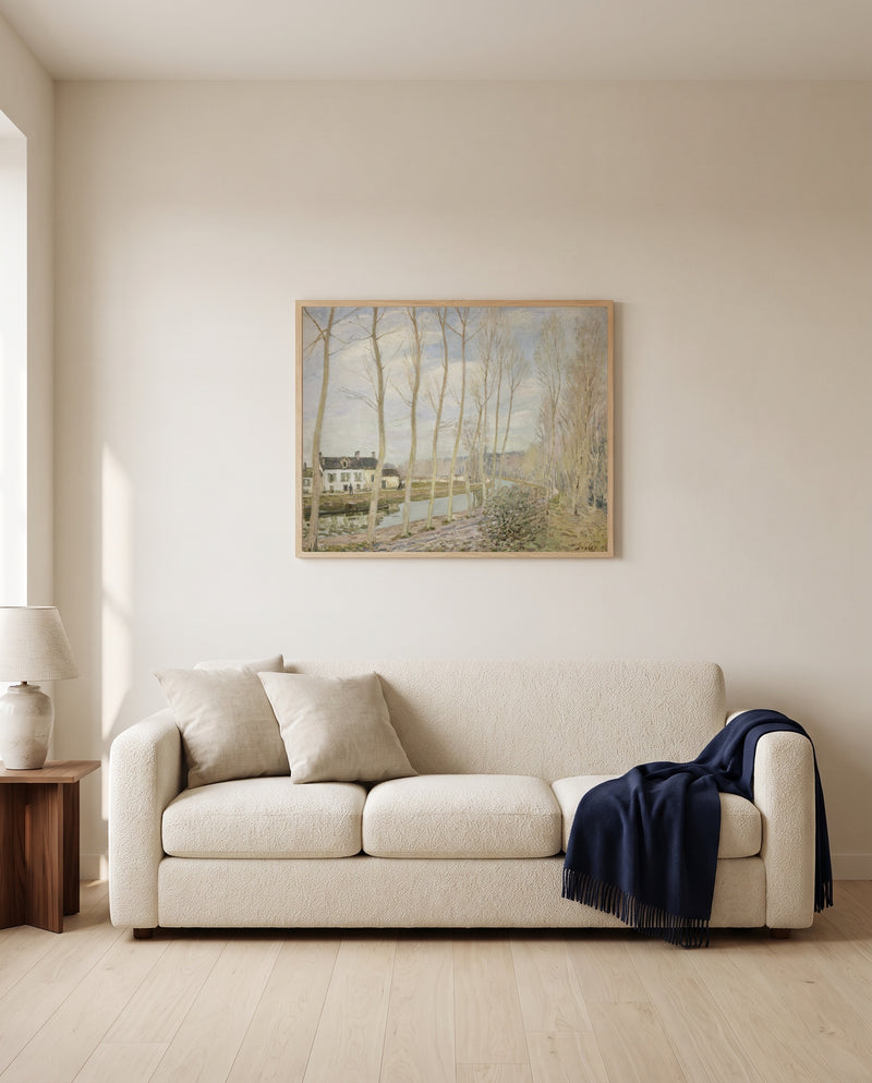 The Canal du Loing by Alfred Sisley framed in natural oak above a cream sofa in a warm living room