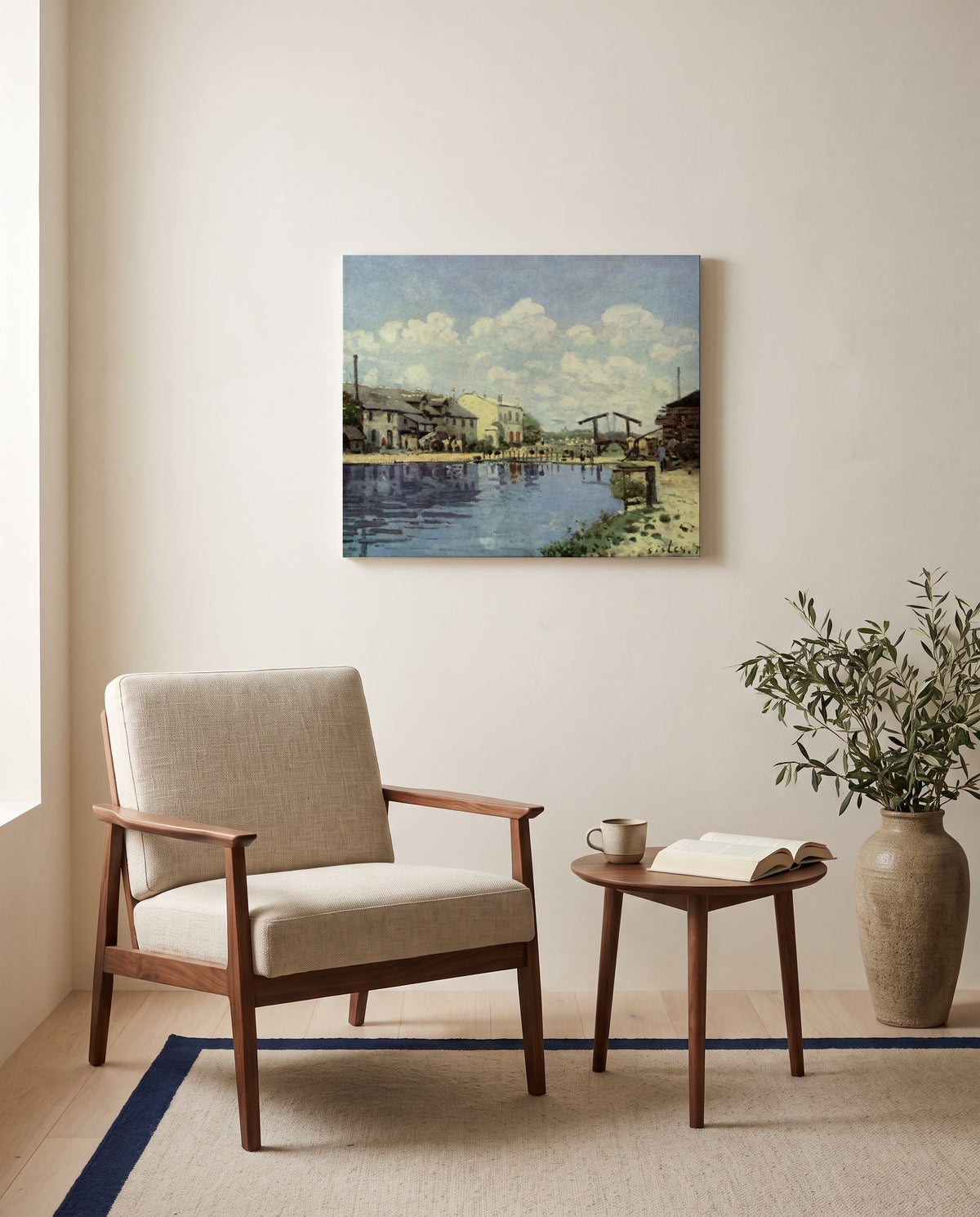 The Canal Saint-Martin by Alfred Sisley as a stretched canvas above a linen lounge chair in a reading corner
