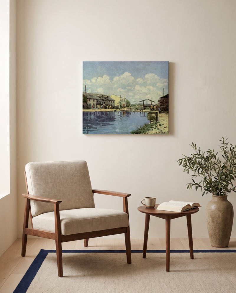 The Canal Saint-Martin by Alfred Sisley as a stretched canvas above a linen lounge chair in a reading corner