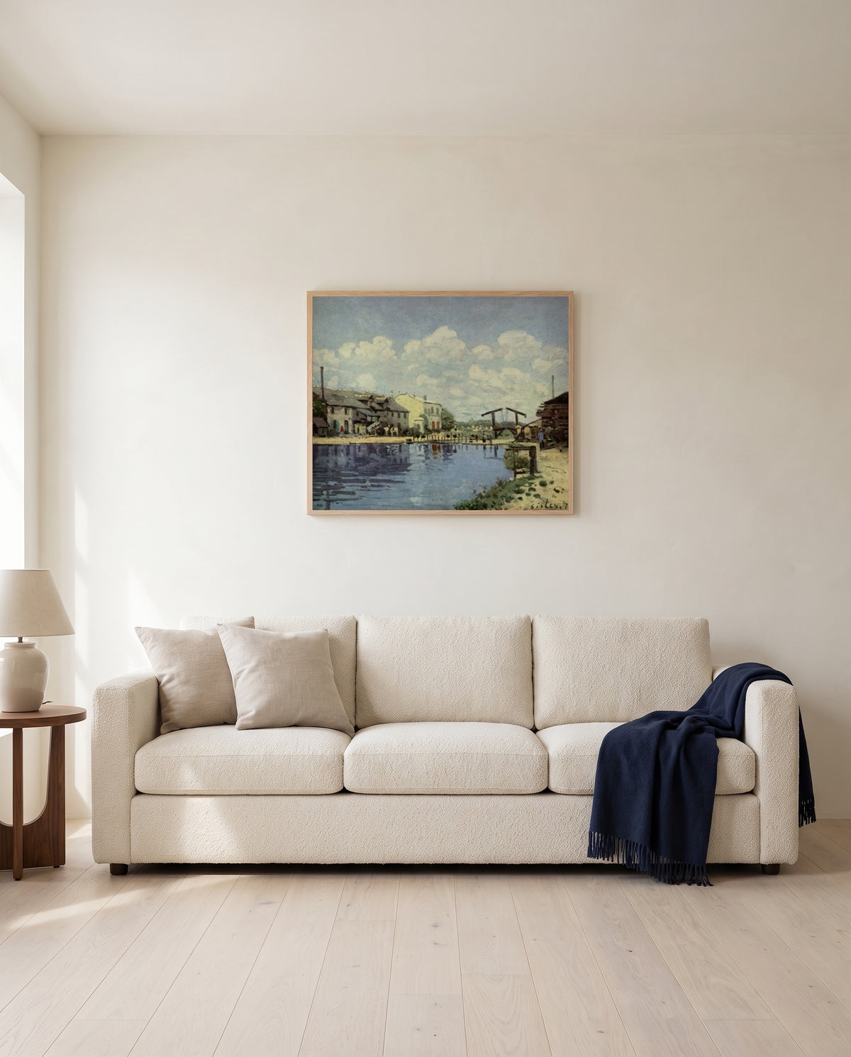 The Canal Saint-Martin by Alfred Sisley framed in natural oak above a cream sofa in a warm living room