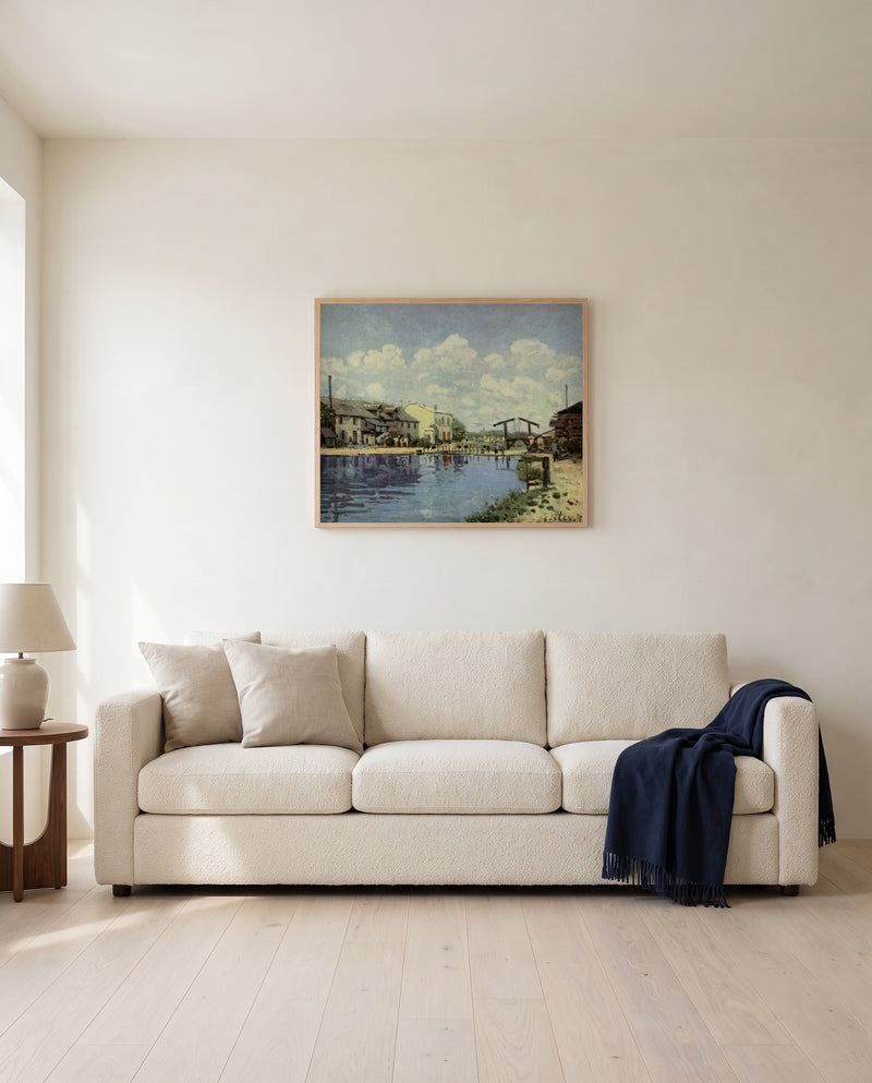 The Canal Saint-Martin by Alfred Sisley framed in natural oak above a cream sofa in a warm living room