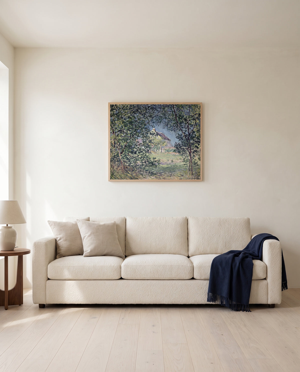 Forest Edge in Spring by Alfred Sisley framed in natural oak above a cream sofa in a warm living room