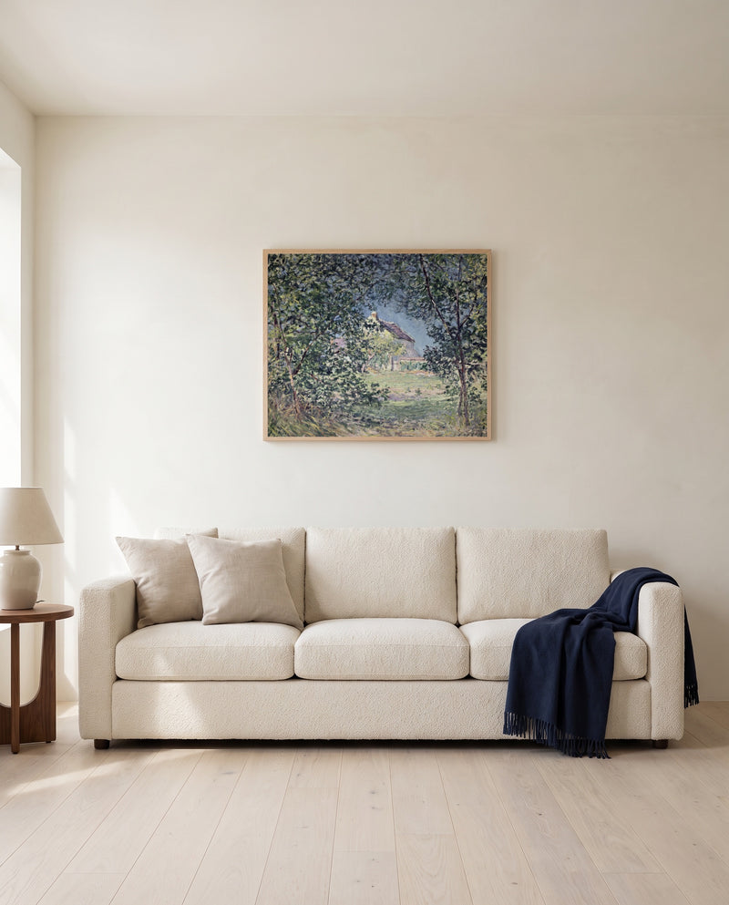Forest Edge in Spring by Alfred Sisley framed in natural oak above a cream sofa in a warm living room