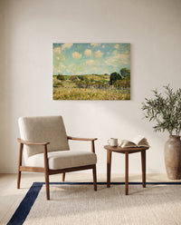 The Meadow by Alfred Sisley as a stretched canvas above a linen lounge chair in a reading corner