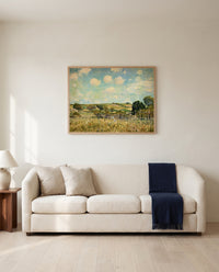 The Meadow by Alfred Sisley framed in natural oak above a cream sofa in a warm living room