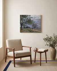 Road to Louveciennes by Alfred Sisley as a stretched canvas above a linen lounge chair in a reading corner