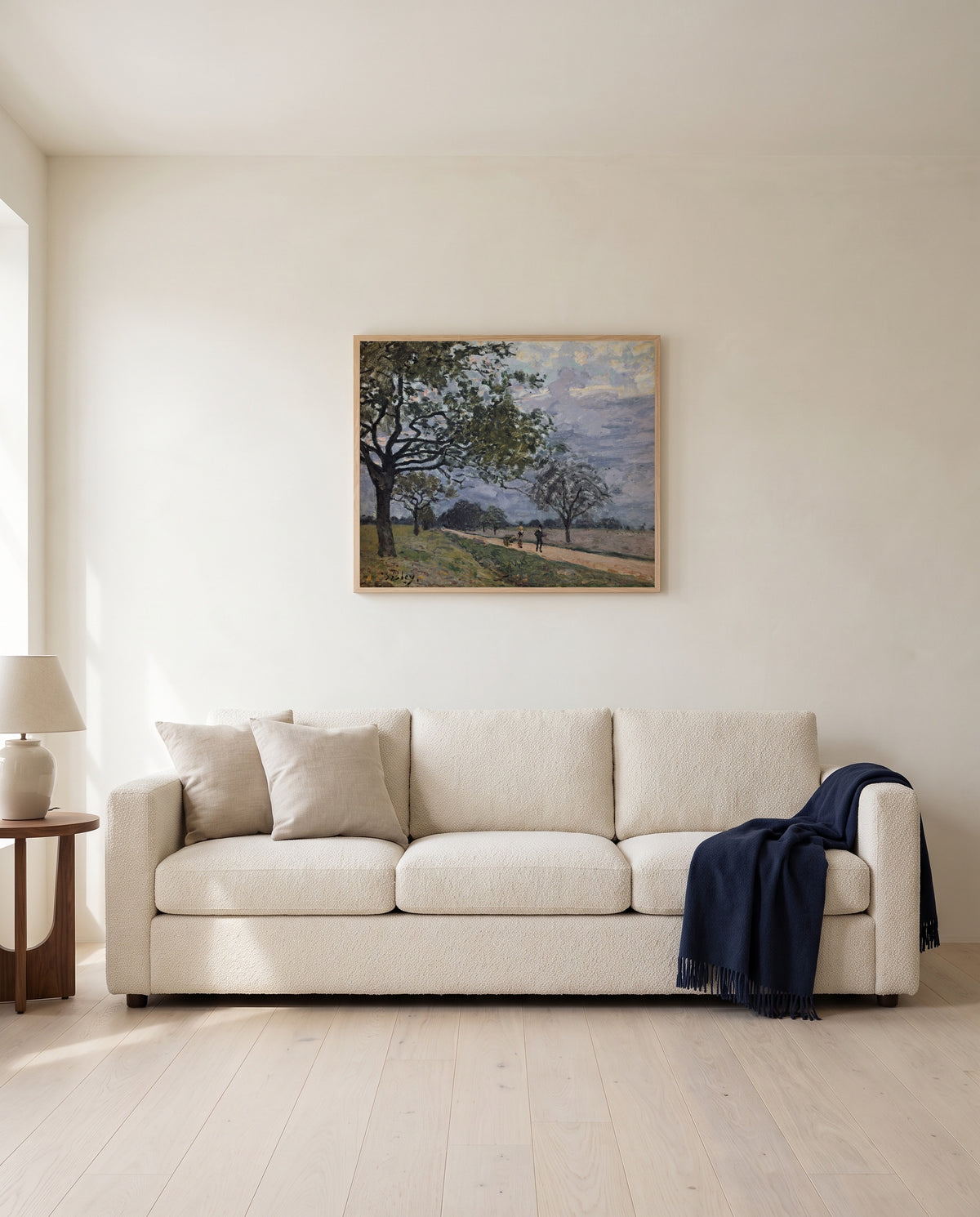 Road to Louveciennes by Alfred Sisley framed in natural oak above a cream sofa in a warm living room