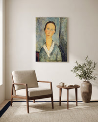 Girl in a Sailor’s Blouse by Amedeo Modigliani as a stretched canvas above a linen lounge chair in a reading corner