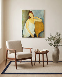 Jeanne Hébuterne (1919) by Amedeo Modigliani as a stretched canvas above a linen lounge chair in a reading corner