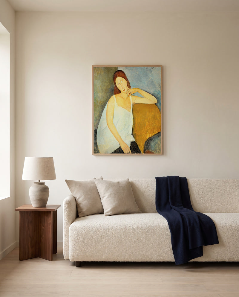 Jeanne Hébuterne (1919) by Amedeo Modigliani framed in natural oak above a cream sofa in a warm living room