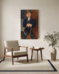 Seated Man with a Cane by Amedeo Modigliani as a stretched canvas above a linen lounge chair in a reading corner