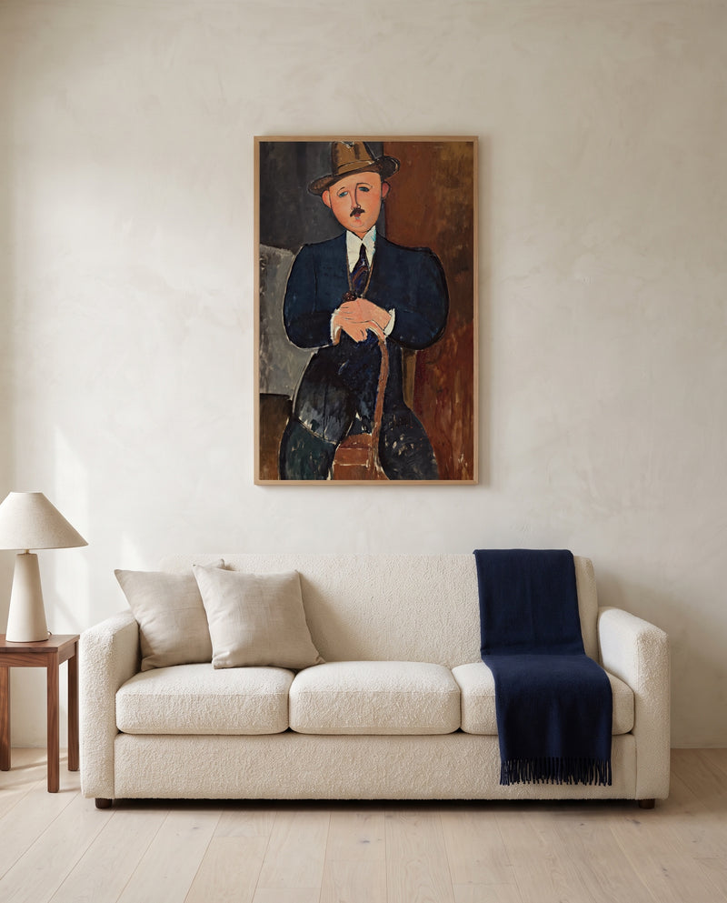 Seated Man with a Cane by Amedeo Modigliani framed in natural oak above a cream sofa in a warm living room