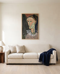 Self-Portrait as Pierrot by Amedeo Modigliani framed in natural oak above a cream sofa in a warm living room