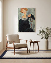 Woman with Red Hair by Amedeo Modigliani as a stretched canvas above a linen lounge chair in a reading corner