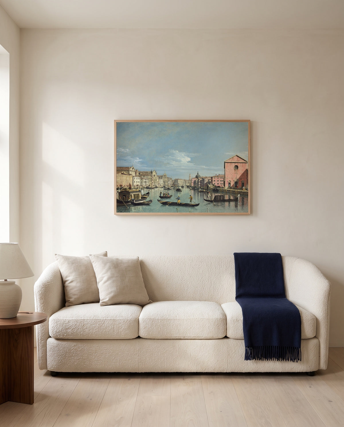 Grand Canal, Santa Croce by Bernardo Bellotto framed in natural oak above a cream sofa in a warm living room