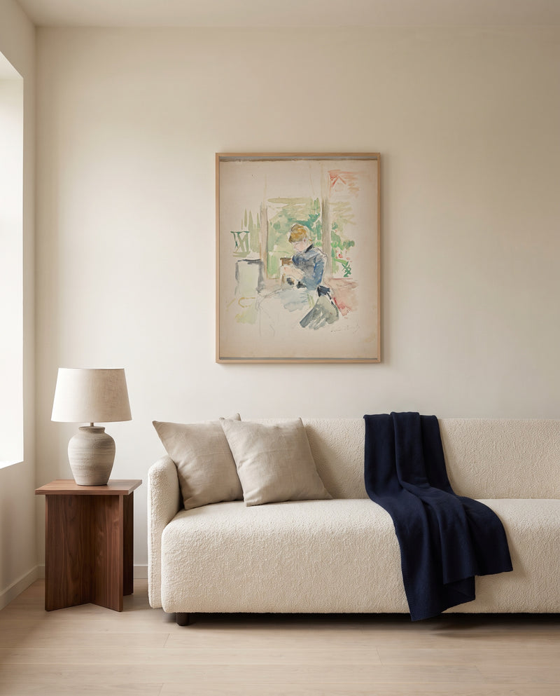 Sewing near the Window by Berthe Morisot framed in natural oak above a cream sofa in a warm living room