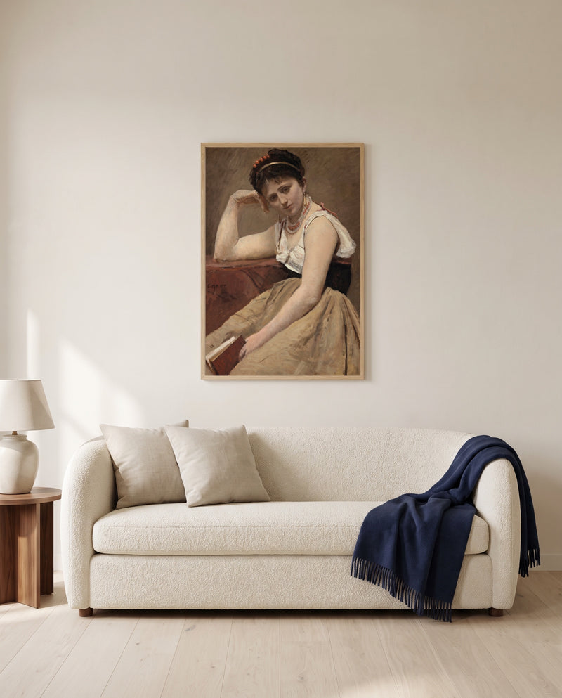 Interrupted Reading by Camille Corot framed in natural oak above a cream sofa in a warm living room