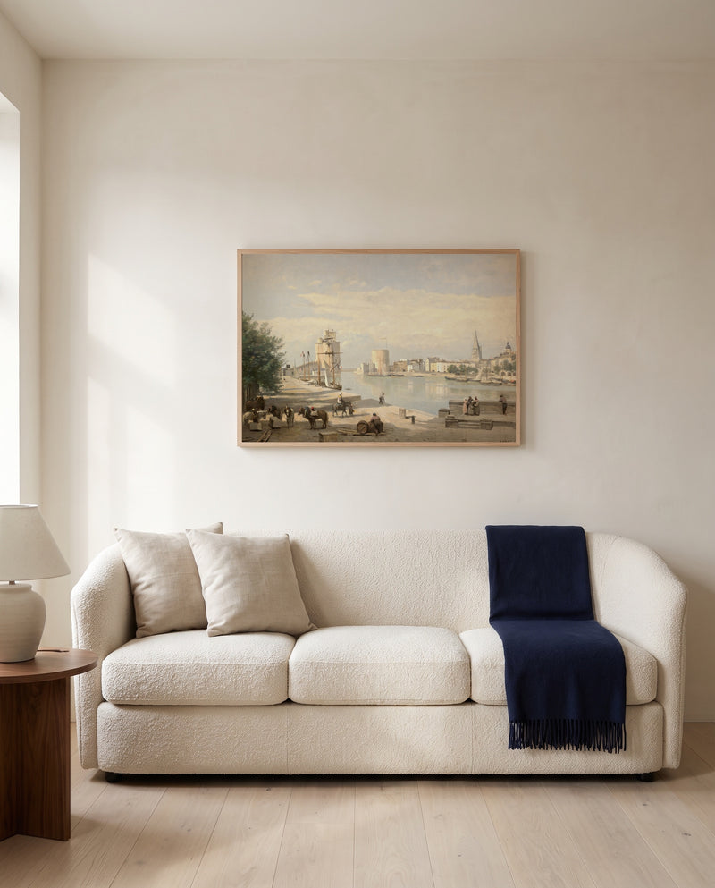The Harbor of La Rochelle by Camille Corot framed in natural oak above a cream sofa in a warm living room