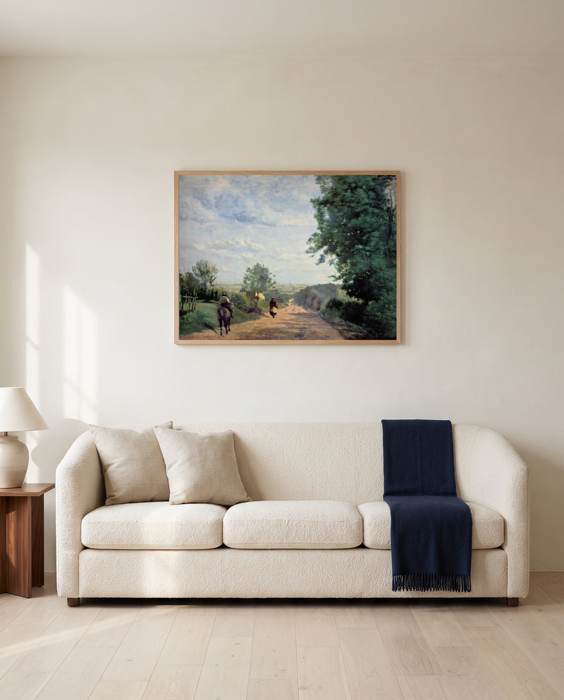 The Road from Sèvres by Camille Corot framed in natural oak above a cream sofa in a warm living room