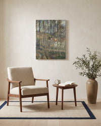 The Côte des Bœufs by Camille Pissarro as a stretched canvas above a linen lounge chair in a reading corner