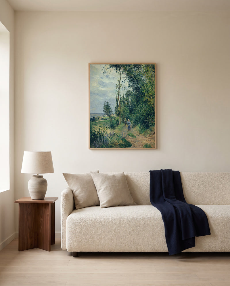 Côte des Grouettes by Camille Pissarro framed in natural oak above a cream sofa in a warm living room