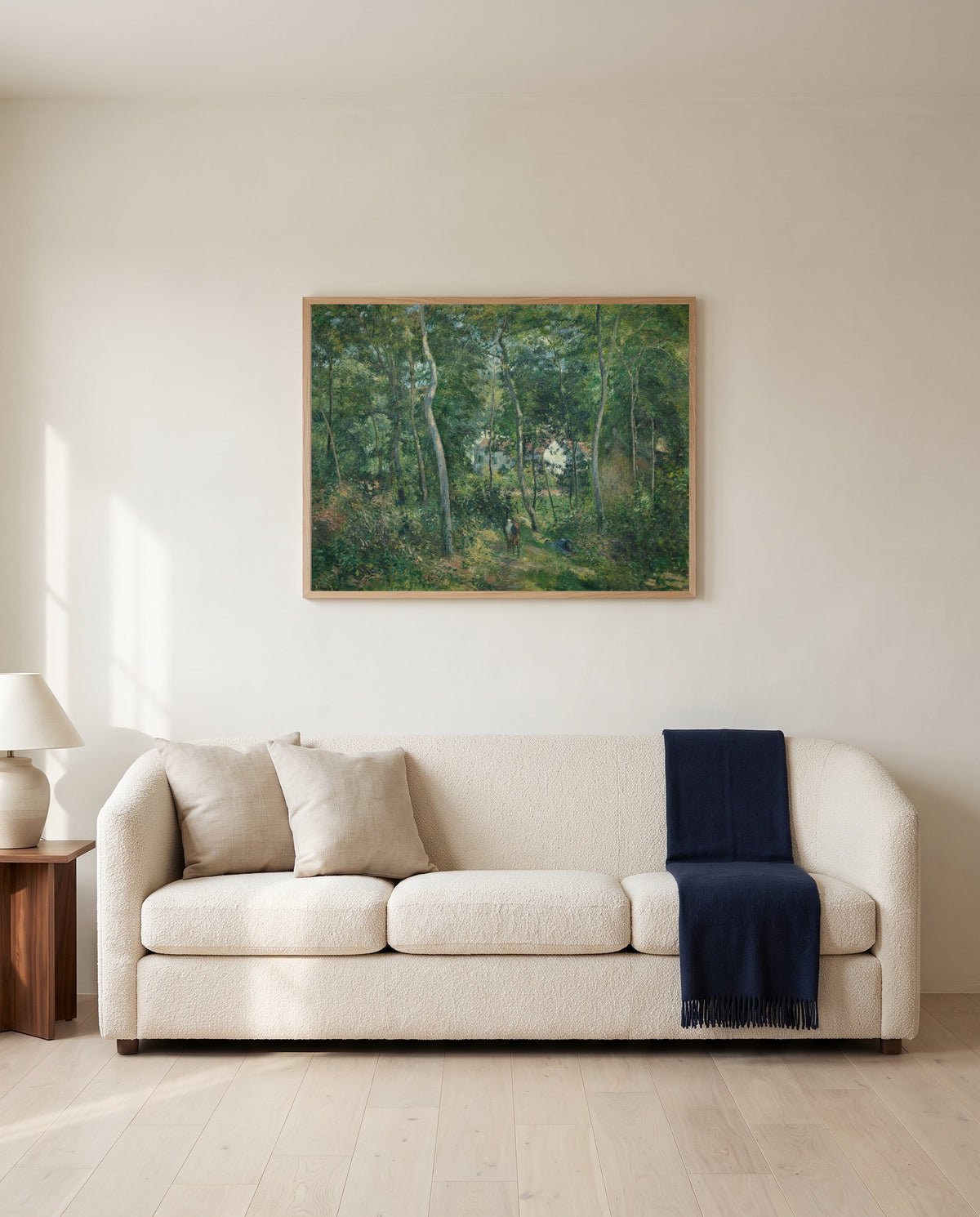 Edge of the Woods, L’Hermitage by Camille Pissarro framed in natural oak above a cream sofa in a warm living room