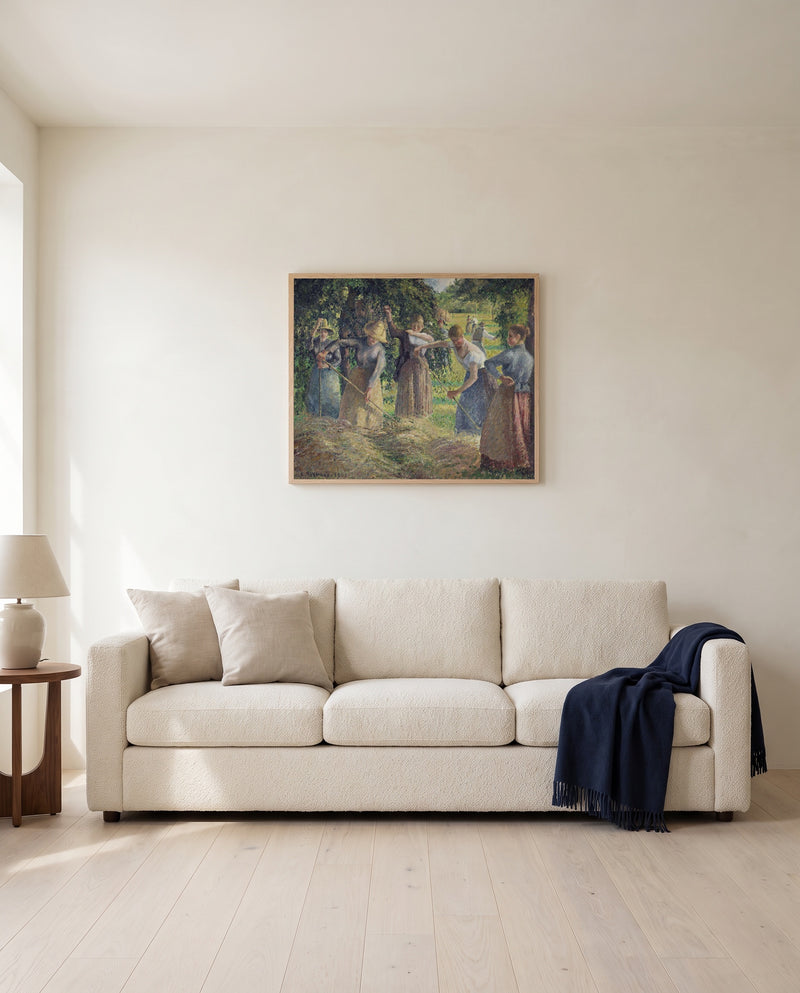 Hay Harvest at Éragny by Camille Pissarro framed in natural oak above a cream sofa in a warm living room