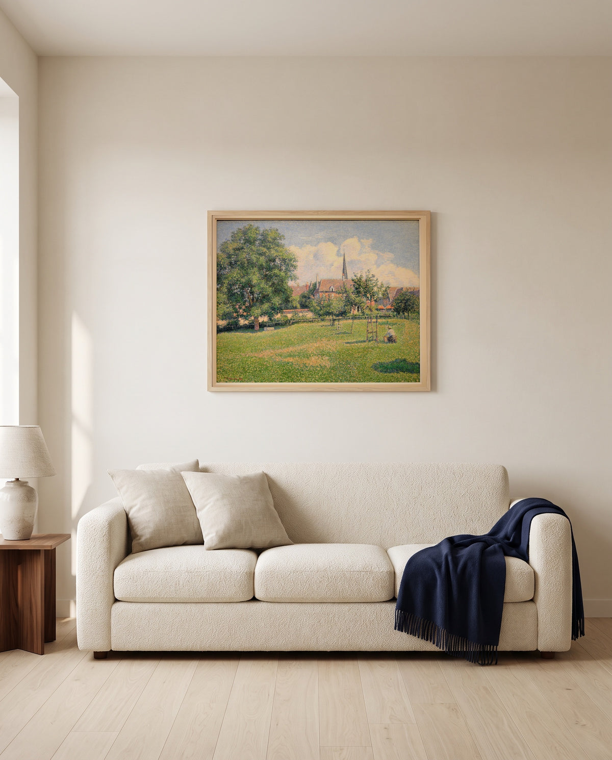 The House of the Deaf Woman by Camille Pissarro framed in natural oak above a cream sofa in a warm living room