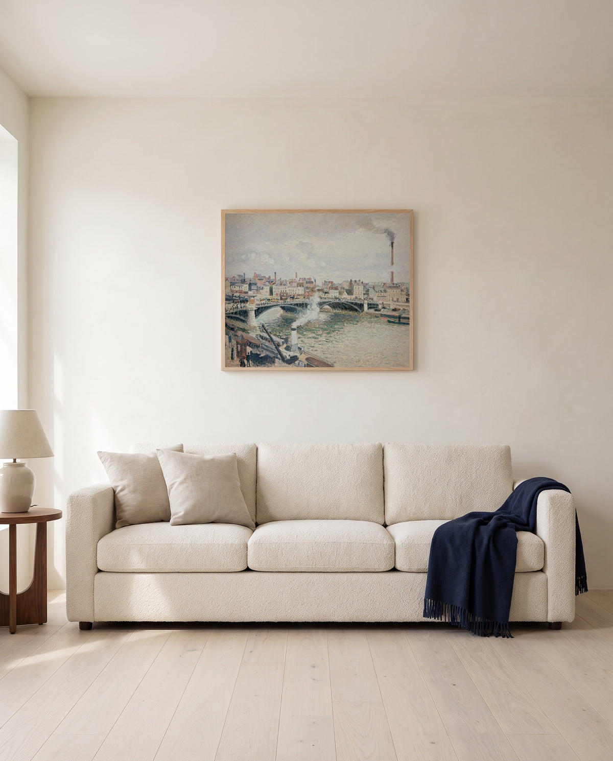Overcast Day, Rouen by Camille Pissarro framed in natural oak above a cream sofa in a warm living room