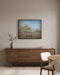 Orchard in Bloom by Camille Pissarro in a black frame above a walnut sideboard in a dining room