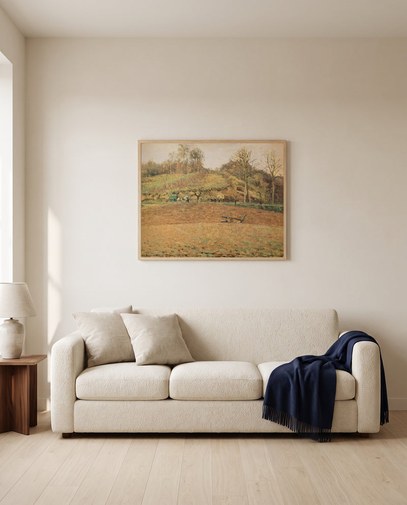 Ploughed Fields by Camille Pissarro framed in natural oak above a cream sofa in a warm living room