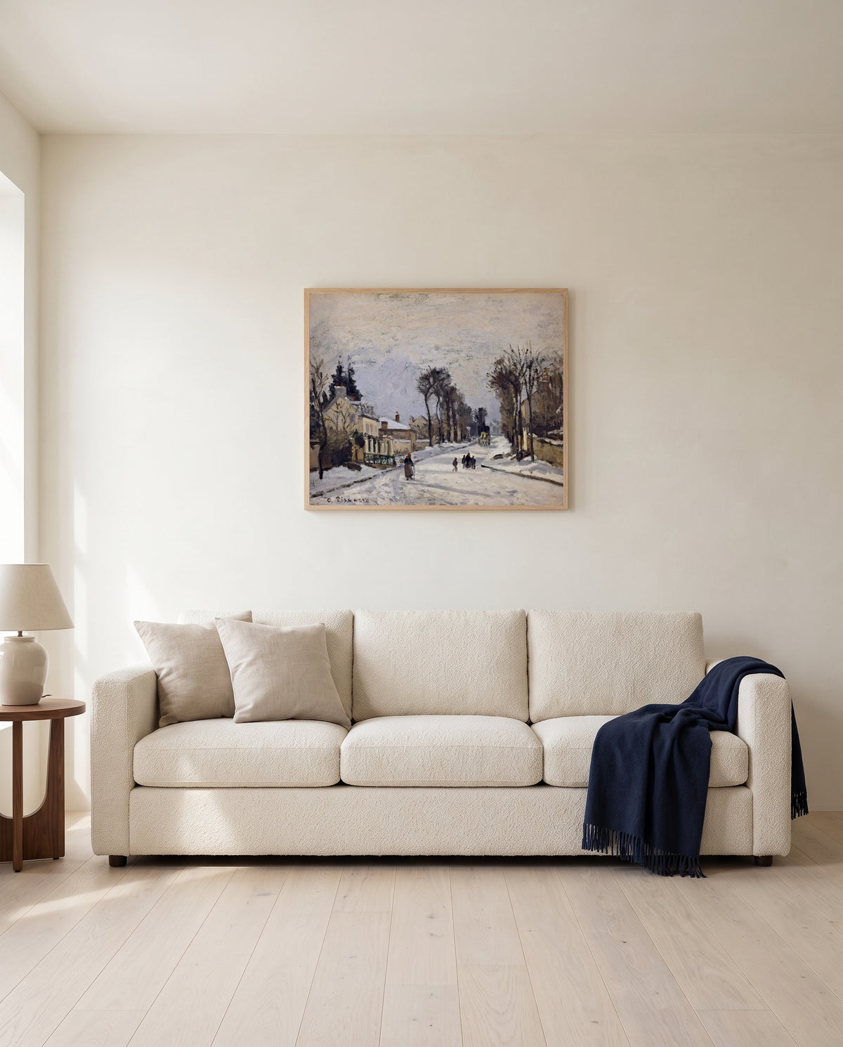 Route to Versailles by Camille Pissarro framed in natural oak above a cream sofa in a warm living room