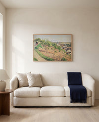 Ruelle des Poulies by Camille Pissarro framed in natural oak above a cream sofa in a warm living room