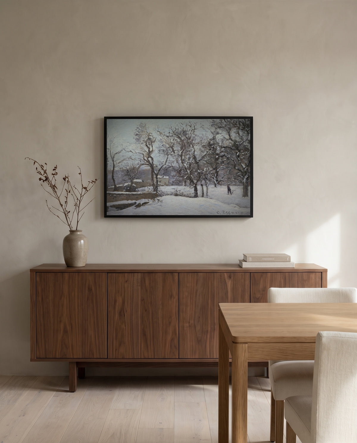 Snow at Louveciennes by Camille Pissarro in a black frame above a walnut sideboard in a dining room