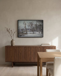 Snow at Louveciennes by Camille Pissarro in a black frame above a walnut sideboard in a dining room