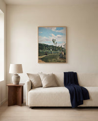 Strollers on a Country Road by Camille Pissarro framed in natural oak above a cream sofa in a warm living room