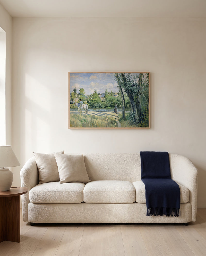 Sunlight on the Road by Camille Pissarro framed in natural oak above a cream sofa in a warm living room