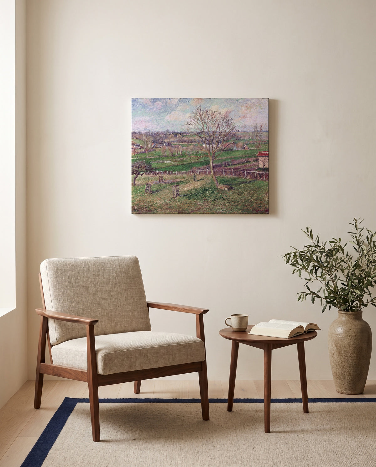 Walnut Tree in Winter by Camille Pissarro as a stretched canvas above a linen lounge chair in a reading corner