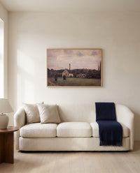 The Little Factory by Camille Pissarro framed in natural oak above a cream sofa in a warm living room