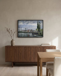 The Lock at Pontoise by Camille Pissarro in a black frame above a walnut sideboard in a dining room